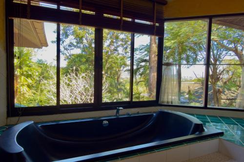 een grote blauwe badkuip in een badkamer met ramen bij Nature's Hill side Phana House in Ban Nong Chaeng