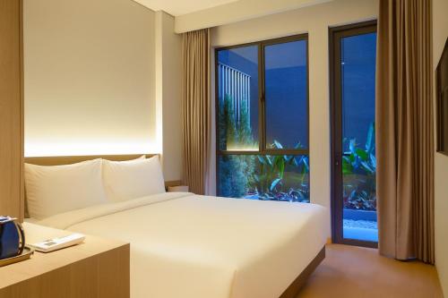 a hotel room with a bed and a large window at The Artha - Bandung in Bandung