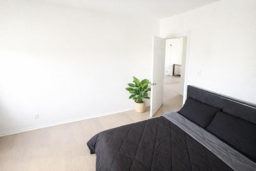 ein Schlafzimmer mit einem schwarzen Bett und einer Pflanze in der Unterkunft Hollywood Comfort Vibe LA in Los Angeles