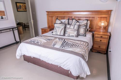 een slaapkamer met een bed met een houten hoofdeinde en kussens bij The Sissing Santuary 