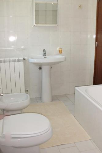 a white bathroom with a toilet and a sink at Quinta das Lindas in Mondim de Basto