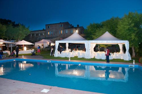 a group of people standing under a tent next to a pool at Fattoria Le Giare Agriturismo in Cortona