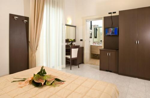 a bedroom with a bed with a television and a bathroom at Hotel Villa Luigia in Rimini