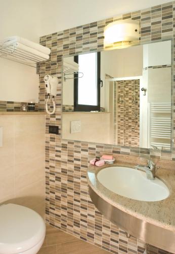 a bathroom with a sink and a toilet and a mirror at Hotel Villa Luigia in Rimini