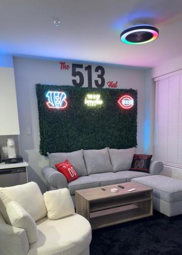 a living room with a couch and signs on the wall at The 513 Flat 2! 1BR, 1Bath Apt with Pool and Riverfront View! Free Gated Parking! Only Steps from The banks & Stadiums! in Cincinnati