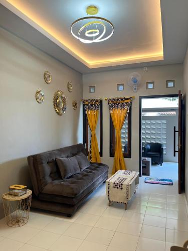 a living room with a leather couch and yellow curtains at ABD Home Blitar syariah at Blitar City in Blitar
