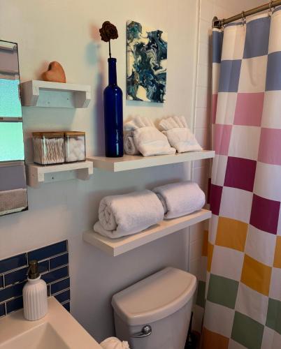 a bathroom with a toilet and shelves with towels at Master Suite with Private Bath 15 min drive to beach in Hilo