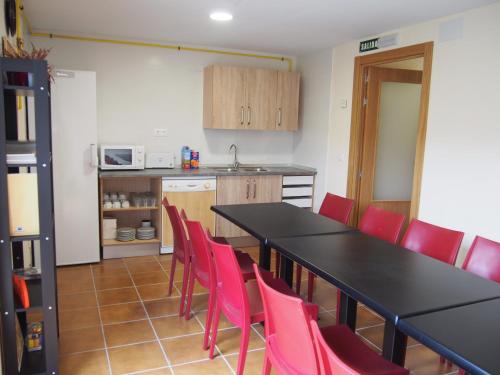 a kitchen with a black table and red chairs at Albergue Segunda Etapa in Zubiri