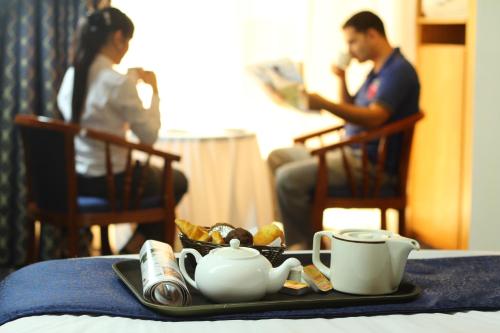 a tray with a tea set on a table with a man and a woman at Cayam Hotel in Doha