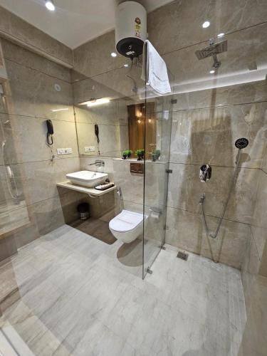 a bathroom with a shower and a toilet and a sink at Travellers Hotel in New Delhi