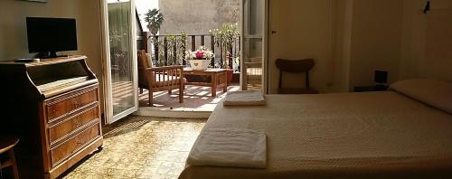 1 dormitorio con cama, TV y balcón en B&b Sulis, en Alghero