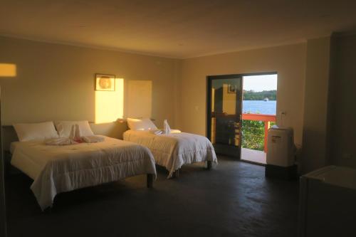 吉佐Zaru Hotel的一间带两张床的卧室和通往阳台的门