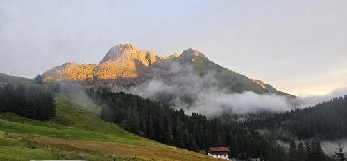 una montagna in lontananza con una casa e alberi di Pension Panorama Warth a Lechleiten