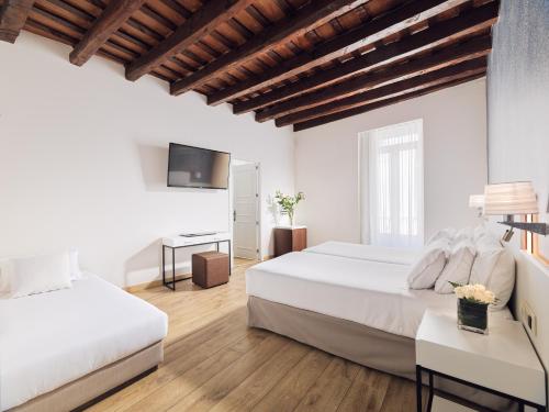 a bedroom with two beds and a flat screen tv at H10 Raco del Pi in Barcelona