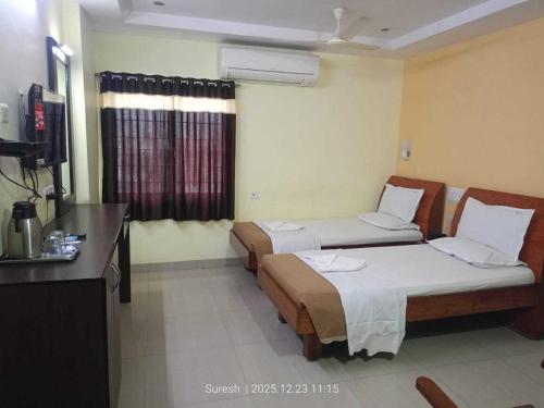 a hotel room with two beds and a television at Challa Residency in Rājahmundry