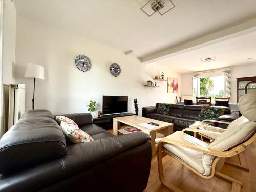 Una sala de estar con un sofá de cuero negro y una mesa. en Holiday House -10 min Clervaux Castle - near forest and shopping - Luxembourg, en Marnach