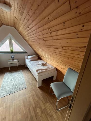 a bedroom with a wooden ceiling with a bed and a chair at Apartmenthaus Eldena Am Teich in Greifswald