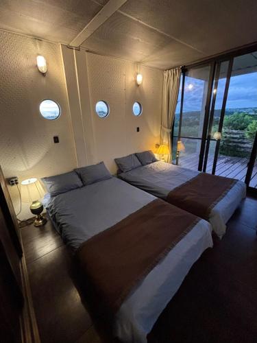 a bedroom with two beds and a balcony at Container Suite 75 in Nago