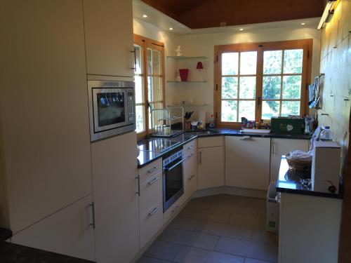 a kitchen with white cabinets and a stove top oven at Chalet Charming in Grächen