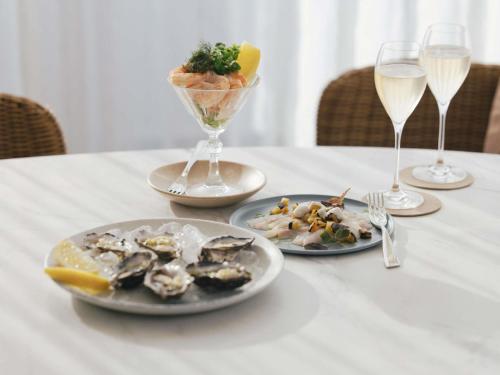 a table with plates of food and glasses of wine at Elysium Noosa Resort - MGallery Collection in Noosa Heads