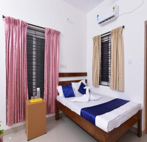 ein Schlafzimmer mit einem Bett und einem Fenster mit Vorhängen in der Unterkunft Pondicherry Comfort Rooms in Puducherry