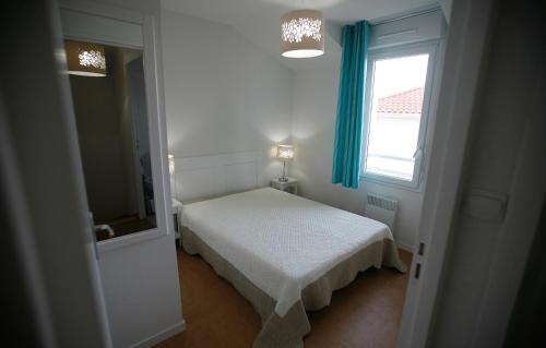 ein kleines Schlafzimmer mit einem Bett und einem Fenster in der Unterkunft Résidence Odalys Le Domaine de l'Océan in Saint-Brévin-lʼOcéan
