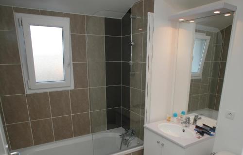 uma casa de banho com uma banheira, um lavatório e um espelho. em Résidence Odalys Le Domaine de l'Océan em Saint-Brévin-lʼOcéan