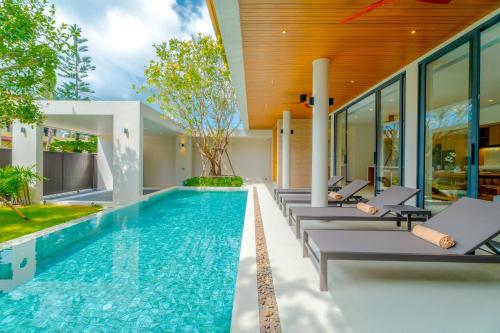 an infinity pool with lounge chairs next to a house at Sava Villa in Ban Saiyuan (1)