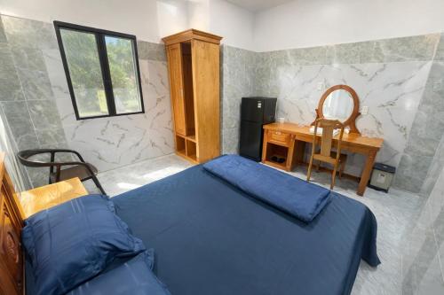 een slaapkamer met een blauw bed en een bureau bij Bình Cơ Hotel in Hoi Nghia