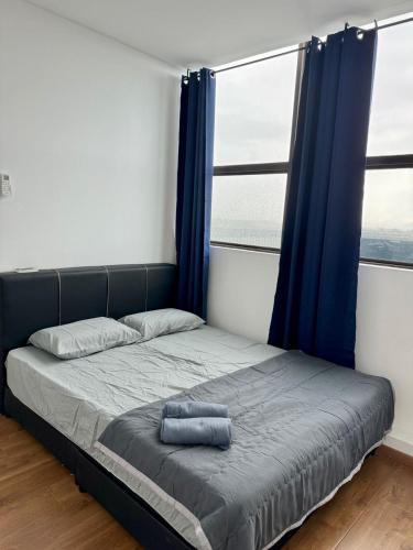 een bed in een kamer met blauwe gordijnen en een bed met een kussen bij Make Memories Escape 2BR Summer Mall Kota Samarahan in Kota Samarahan