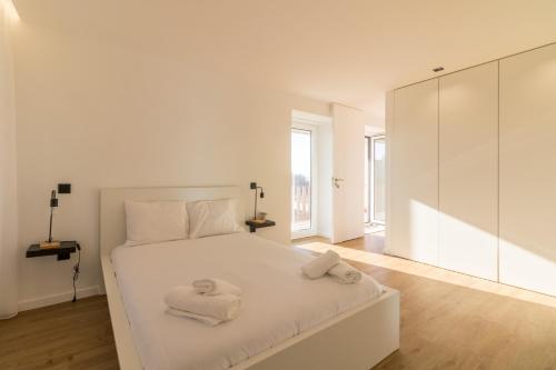 a white bedroom with a large white bed with towels on it at Solar dos Arcos • Luxury Rural Retreat & Heated Po in Macieira da Lixa