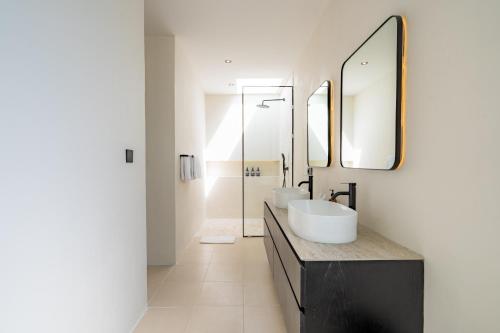 een badkamer met twee wastafels en een spiegel bij Black Villa by Betterplace in Tanah Lot