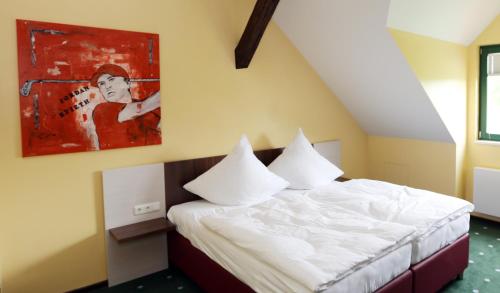 ein Schlafzimmer mit einem Bett und einem Gemälde an der Wand in der Unterkunft Apartments Golfpark Schlossgut Sickendorf in Lauterbach
