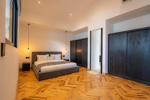 een slaapkamer met een bed en een houten vloer bij Black Villa by Betterplace in Tanah Lot