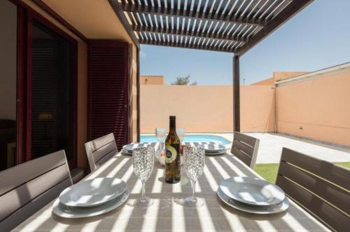 a table with a bottle of wine and plates on it at Tajora House by Best Holidays Fuerteventura in La Oliva