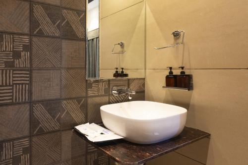 een badkamer met een witte wastafel en een spiegel bij Pravasa Stay Near Luv Kush Square in Indore