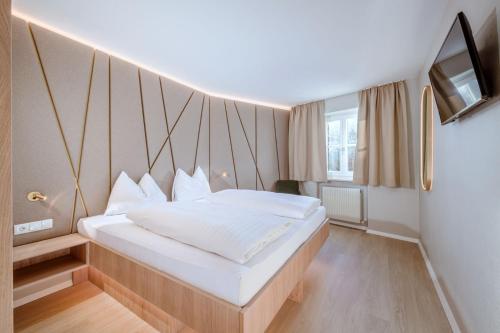 a bedroom with a large white bed and a tv at Crystls Aparthotel in Flachau