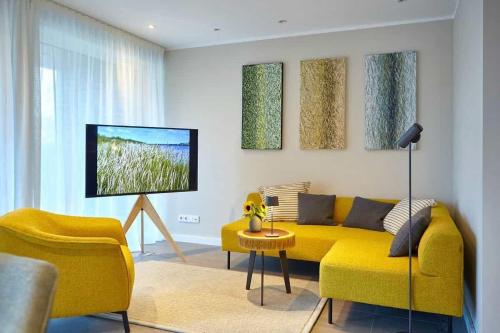 een woonkamer met een gele bank en een tv bij Die-perfekte-Ferienvilla in Butjadingen