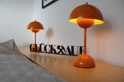 two orange lamps sitting on top of a wooden table at GlückAufBud Schwarzenberg WLAN Netflix Stellplatz in Schwarzenberg/Erzgebirge