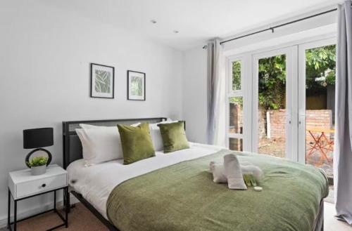a white bedroom with a large bed with a window at Hot Tub Emerald Escape - Private Garden & Free Parking in Cardiff