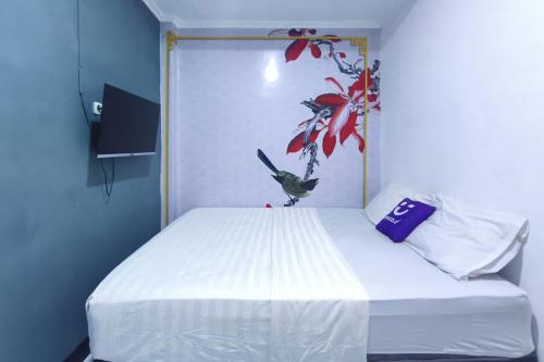 een slaapkamer met een wit bed met een schilderij aan de muur bij INNCA - Dream Memory, Semarang in Kalibanteng-lor
