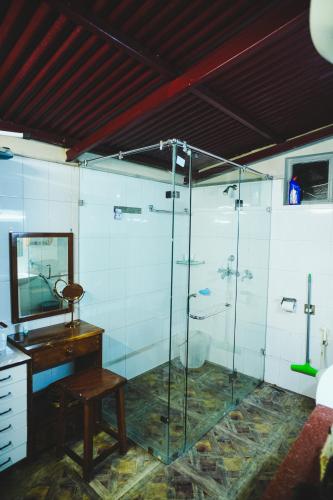 a bathroom with a shower with a sink and a mirror at The River Trail Cottage by The StayCationer in Rājpur