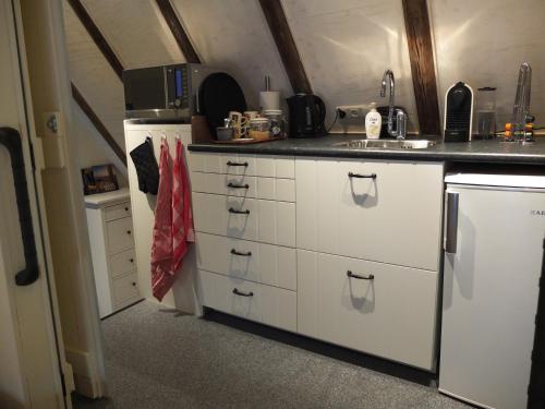 La cuisine est équipée de placards blancs, d'un évier et d'un réfrigérateur. dans l'établissement De Wiede Blik, à Westerbroek