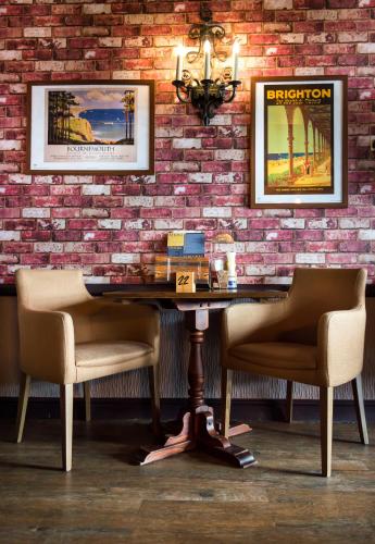 a table with two chairs and a brick wall at Suncliff Hotel - OCEANA COLLECTION in Bournemouth