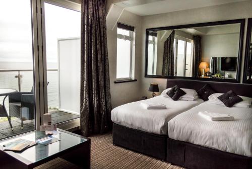 a bedroom with a large bed and a mirror at Suncliff Hotel - OCEANA COLLECTION in Bournemouth