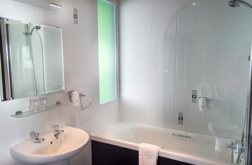 a bathroom with a sink and a tub and a mirror at Suncliff Hotel - OCEANA COLLECTION in Bournemouth