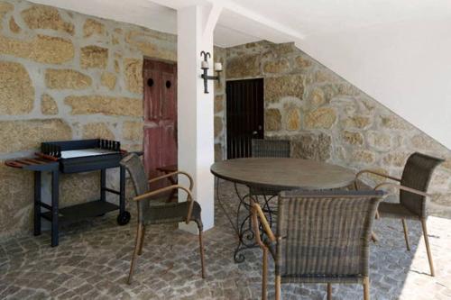 a table and chairs in a room with a stone wall at Villa Lugar do Pego in Tondela