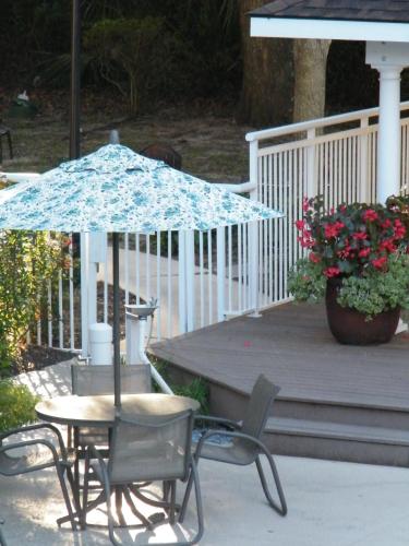 a table and chairs with an umbrella on a porch at Palmera Inn and Suites in Hilton Head Island