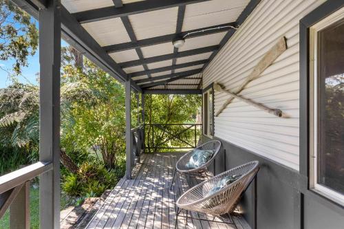 a porch with two chairs and awning at Ma Te Kokorou - pet-friendly Huskisson pool escape in Huskisson