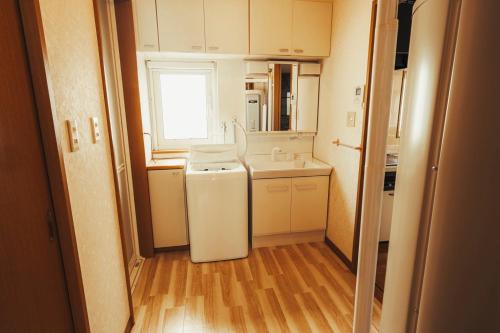 Elle comprend une petite cuisine avec un réfrigérateur et une fenêtre. dans l'établissement 南町ハウス, à Biei